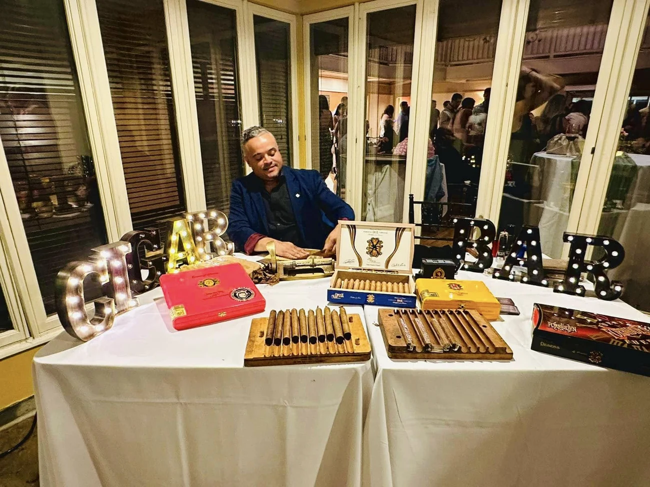 Franklin Pichardo seated at a long table with rows of finished cigars in front of him