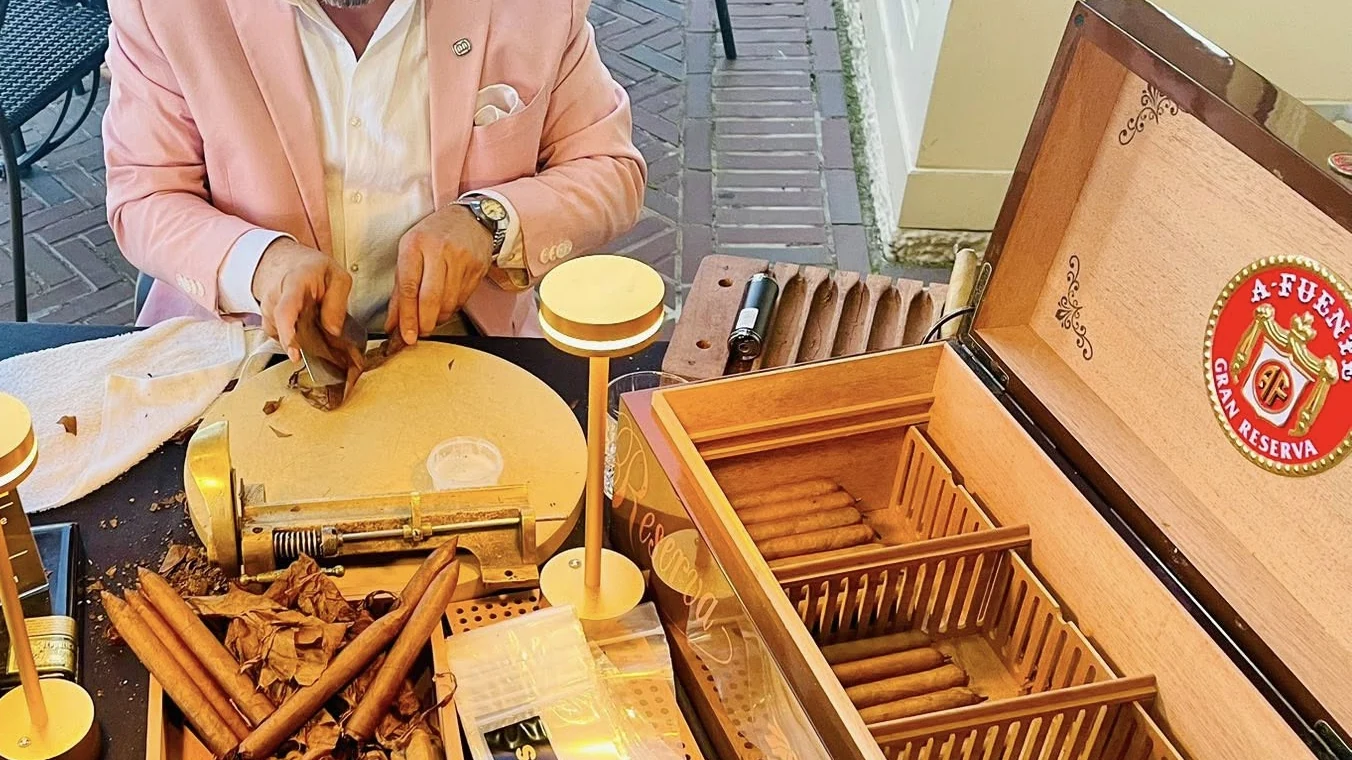 Hands over an open humidor of cigars, with the press and the board beside it