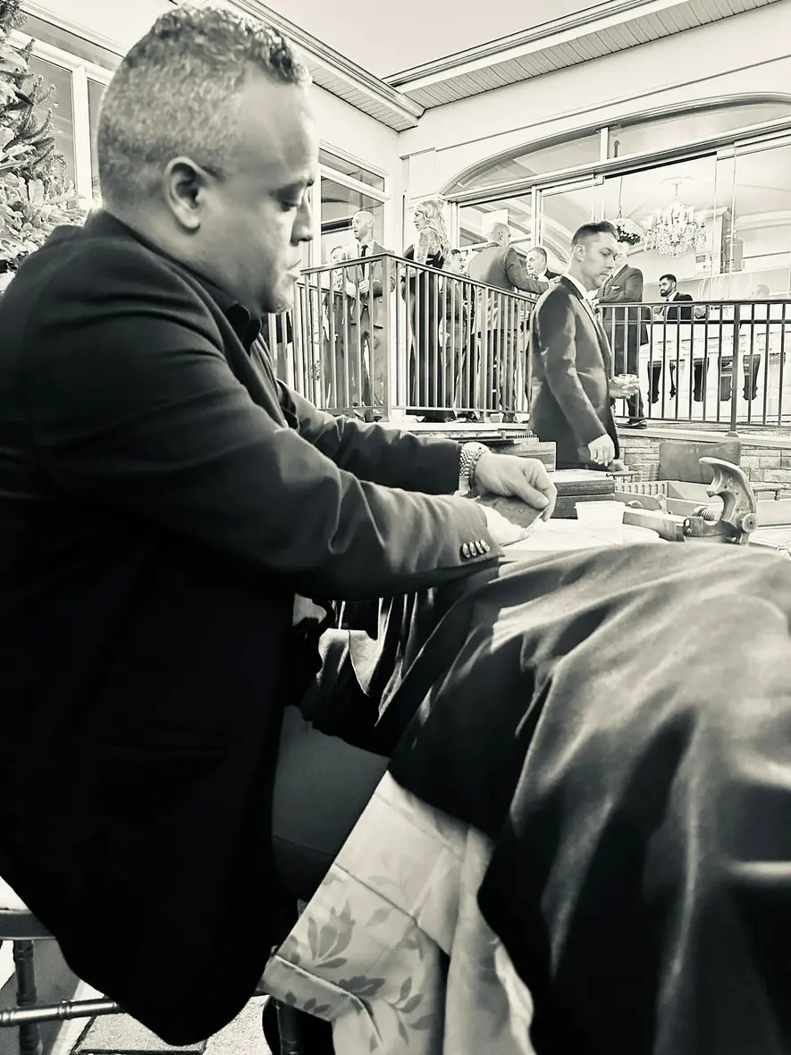 Franklin rolling at his table, wedding guests on the terrace behind him