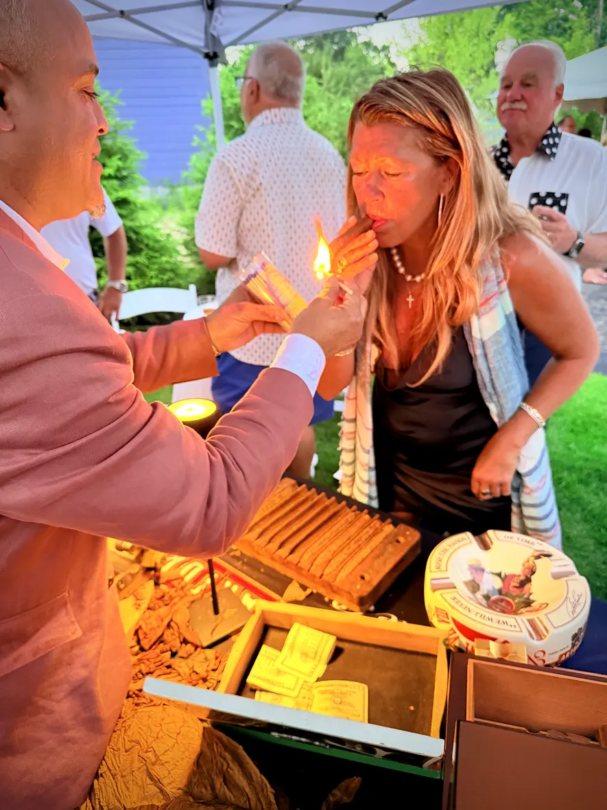 Franklin lighting a guest’s cigar under a white tent