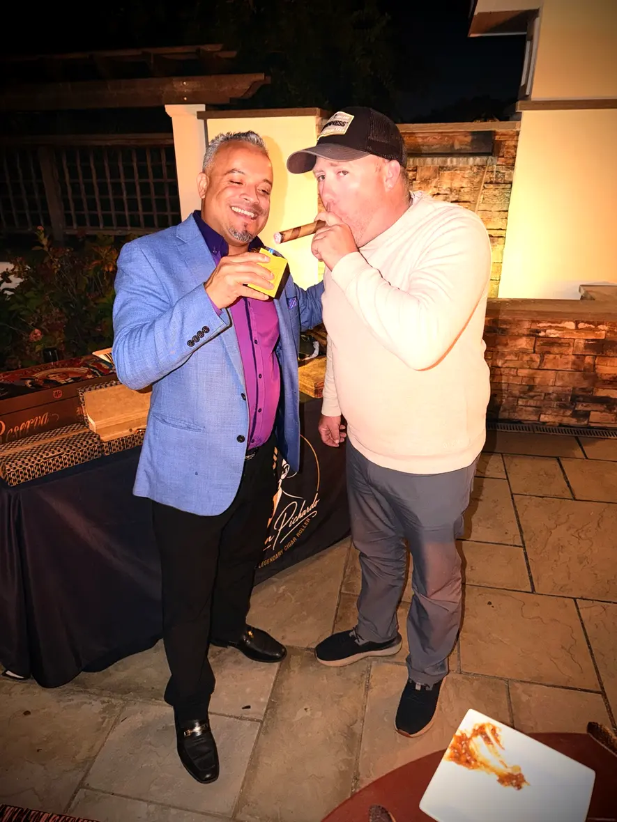 Franklin lighting a guest’s cigar on the stone terrace at night