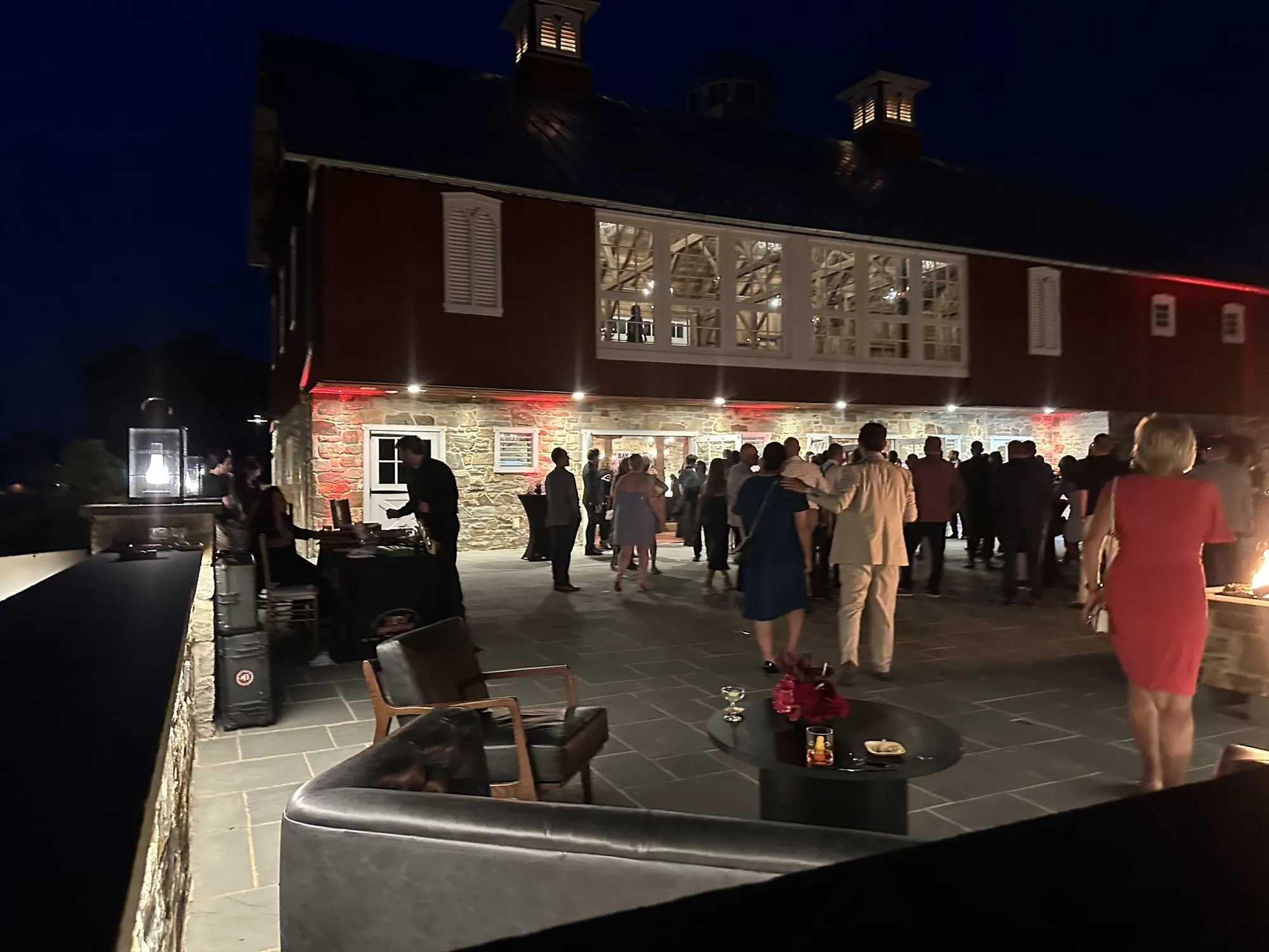 A stone barn lit up at night, its terrace full of guests, with Franklin Pichardo standing at his table on the left